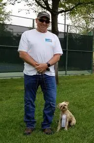 A man and his dog are standing in the grass.